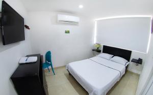 een slaapkamer met een wit bed en een blauwe stoel bij Hotel Embajador del Llano in Villavicencio