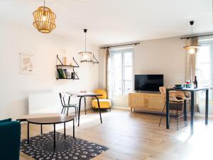 ein Wohnzimmer mit 2 Tischen und einem TV in der Unterkunft Le Saunerie - Sleep in Sisteron in Sisteron