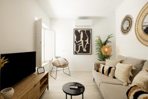a living room with a couch and a tv at Apartamento Mucha Vida Little Apartments in Cádiz