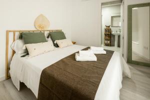 - une chambre avec un grand lit et des serviettes dans l'établissement Apartamento Mucha Vida Little Apartments, à Cadix