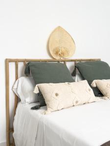 - un lit avec des draps blancs et des oreillers verts dans l'établissement Apartamento Mucha Vida Little Apartments, à Cadix