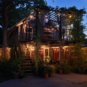 Cedar Oaks Inn The Birdcage Saloon في ديكنسون: منزل مع شرفة مع أضواء عليه