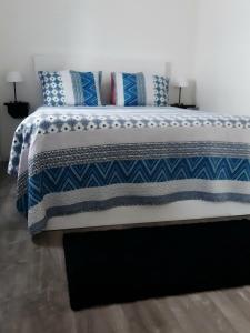 a bed with blue and white blankets and pillows on it at Villa Sofia in Foz do Arelho