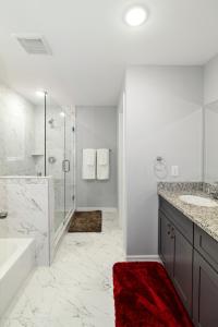 a white bathroom with a shower and a red rug at PEERLESS RETREAT - Minutes from Downtown Houston in Houston
