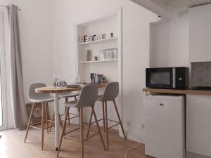 une cuisine avec une table avec des chaises et un micro-ondes dans l'établissement Studio mezzanine hyper centre, au pied du castillet, à Perpignan 10 autres photos