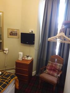 a hotel room with a bed and a chair and a tv at The City in Edinburgh