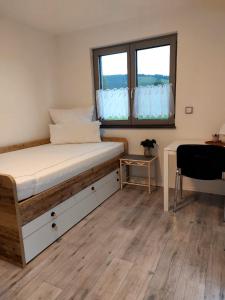 a bedroom with a bed with a window and a desk at Ferienhaus Rasch in Maierhöfen