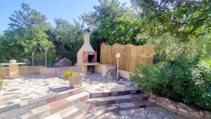 un jardín con un patio de piedra con chimenea en Doxina - Belocations, en Sinnai