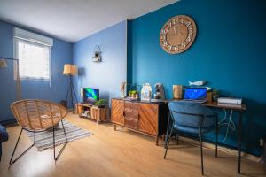a room with a desk and a clock on a blue wall at L'Effet-Mer - Tout équipé - Parking Privé - Wifi in Saint-Nazaire