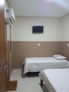 um quarto com duas camas e uma televisão na parede em Center Prime Hotel em Bom Jesus da Lapa