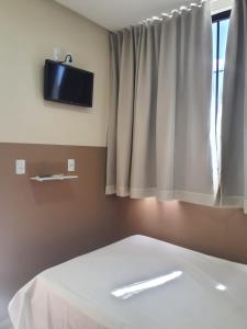 ein Schlafzimmer mit einem Bett und einem TV an der Wand in der Unterkunft Center Prime Hotel in Bom Jesus da Lapa