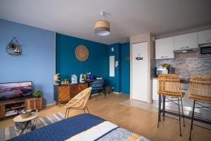 a living room with blue walls and chairs and a kitchen at L'Effet-Mer - Tout équipé - Parking Privé - Wifi in Saint-Nazaire