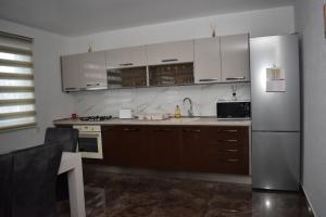 uma cozinha com armários brancos e um frigorífico de aço inoxidável em Casa Dumitru 2 em Valea Borului
