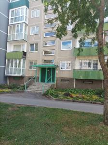 a building with a green door and stairs in front of it at Centrinio parko apartamentai in Šiauliai