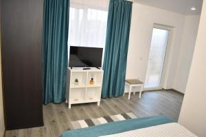 1 dormitorio con 1 cama, TV y cortinas en Casa Dumitru 2, en Valea Borului
