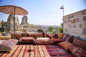 a couch with pillows and an umbrella on a balcony at House 1938 Special Cave Hotel in Ortahisar