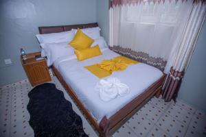 1 cama con almohadas amarillas y blancas y ventana en Heritage Villa Hotel & Accomodation, en Kericho