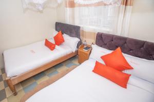 2 Betten mit orangefarbenen Kissen in einem Zimmer in der Unterkunft Heritage Villa Hotel & Accomodation in Kericho