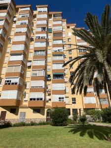 阿爾加羅沃科斯塔的住宿－Bonito Apartamento en Algarrobo-Costa，一座高大的建筑,前面有一棵棕榈树