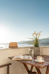 Mira Sitia Luxury Apartment في سيتيا: طاولة مع كتاب مفتوح وكوب من القهوة