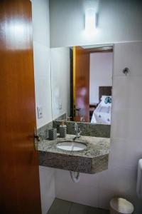 a bathroom with a sink and a mirror at Pousada Enseada da Ilha in Capitólio