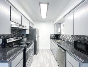a kitchen with stainless steel appliances and black counter tops at Trendy Ivy 2-bedroom Apartment Near Dt Coalinga in Coalinga