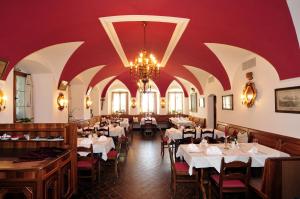 a restaurant with white tables and chairs and a chandelier at Hotel-Gasthof Maria Plain in Bergheim