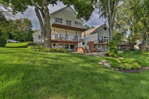 a large house with a large yard with green grass at Homey Lakefront Hideaway with 2 Decks and Dock! in Fenton