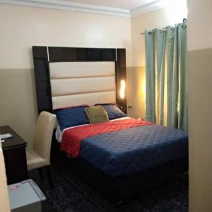 a bedroom with a bed and a desk and a chair at Asaba Gardens and Resort in Asaba