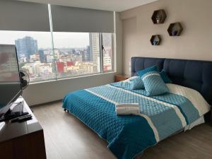 ein Schlafzimmer mit einem blauen Bett und einem großen Fenster in der Unterkunft WTC Suites in Mexiko-Stadt