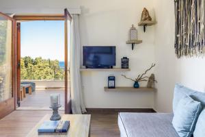 a living room with a couch and a tv at The Sea House Skiathos in Skiathos
