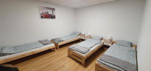 a group of beds in a room with wooden floors at KOKON Noclegi Żuromin in Żuromin