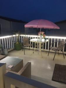 un patio con una mesa y una sombrilla rosa en Summer Breeze en Bude