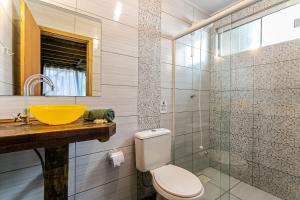 uma casa de banho com um lavatório amarelo e um WC. em Moradas do Vale Praia do Rosa em Praia do Rosa