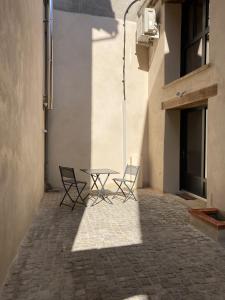 eine Terrasse mit 2 Stühlen und einem Tisch in einem Gebäude in der Unterkunft L ATELIER cour clim 3 ETOILES in Moissac