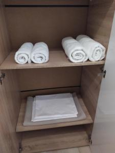 - un placard avec des serviettes blanches sur une étagère dans l'établissement Rania's house, à Thessalonique