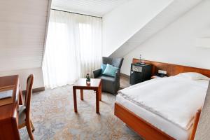 una camera con letto, sedia e tavolo di Hotel und Gutsgaststätte Rappenhof a Weinsberg