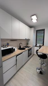 a kitchen with white cabinets and a table and a stool at Nathallie Modern Apartments in Timişoara