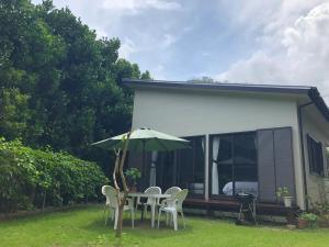 une terrasse avec une table, des chaises et un parasol dans l'établissement Fukugi no Yado - Vacation STAY 94994v, à Amami