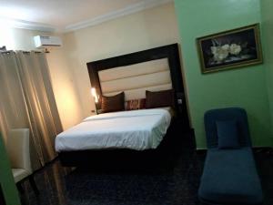 a bedroom with a large bed and a blue chair at Asaba Gardens and Resort in Asaba