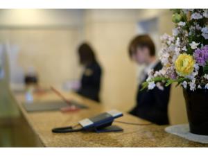 a woman sitting at a counter with a vase of flowers at Hotel Ronshan Sapporo - Vacation STAY 64963v in Sapporo