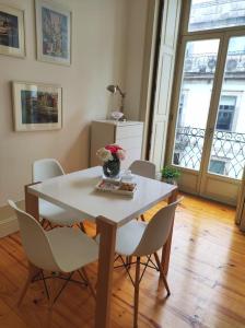 a table with chairs and a vase of flowers on it at Our Home City Flat in Porto