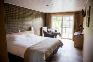 a bedroom with a bed and a table with a chair at B&B De Bergvallei in Oedelem