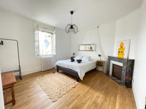 Dormitorio blanco con cama y chimenea en DOMFRONT-BNB : CHIC & CONFORT en Domfront
