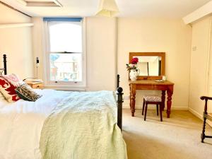a bedroom with a bed and a table and a mirror at Charming 2 bed flat market square in Oxfordshire in Grove