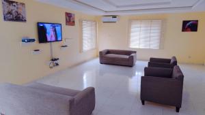 a living room with two chairs and a flat screen tv at Abuja Apartments 24 in Abuja