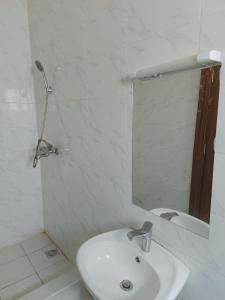 a white bathroom with a sink and a mirror at Abuja Apartments 24 in Abuja