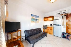 a living room with a leather couch and a refrigerator at Mayan Falls Gold Standard and Corridor Certified in Caye Caulker