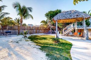 a house with a straw umbrella and a fence at Mayan Falls Gold Standard and Corridor Certified in Caye Caulker