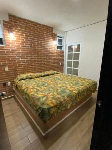 a bed in a room with a brick wall at Hotel Villas La Mexicana in Tecozautla